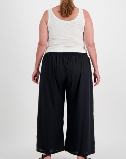 Person wearing a white sleeveless modal top and black wide-leg pants on a white background