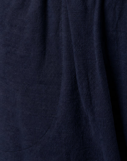Close-up of dark navy blue textured cotton fabric with soft folds and a subtle woven linen-like surface.