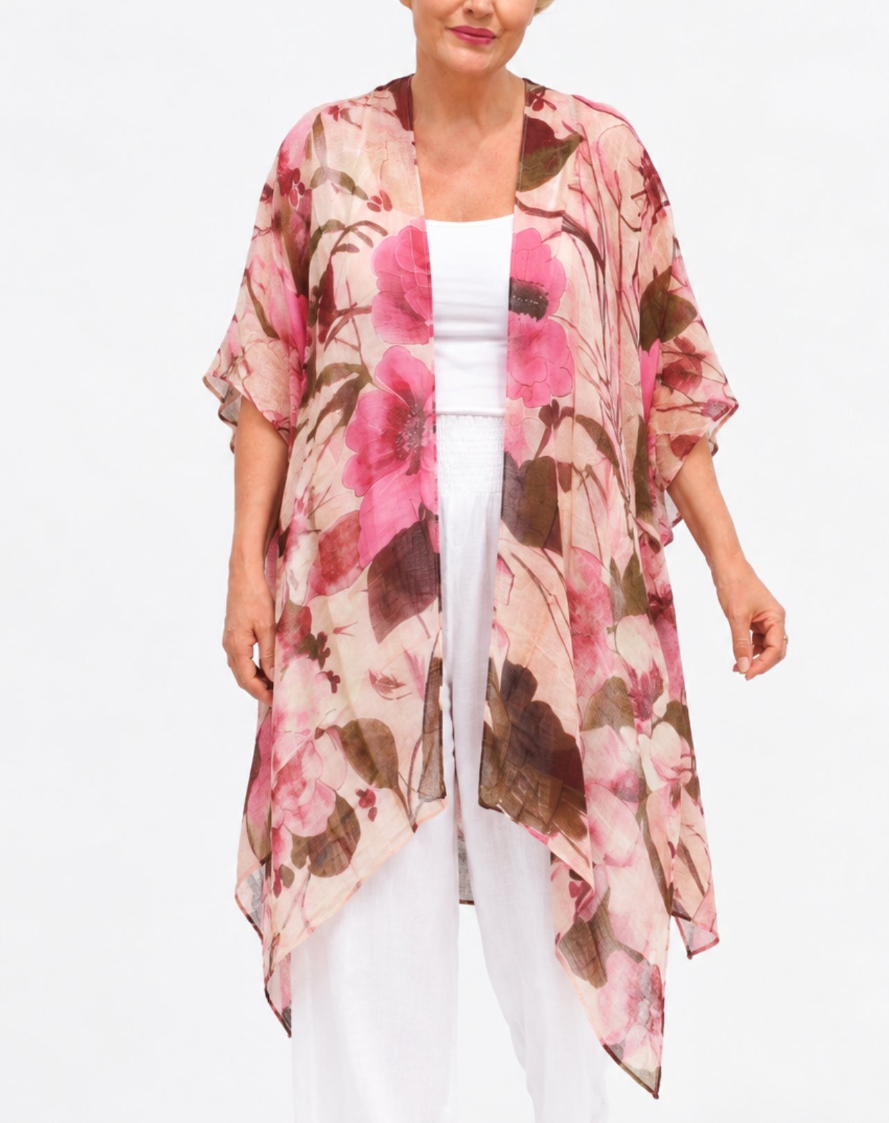 A woman wearing a lightweight floral kimono cardigan with pink, brown, and beige tones over a white top and white pants, photographed against a plain white studio background.
