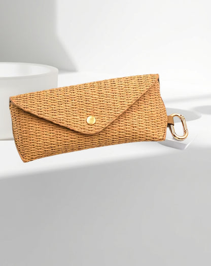Woven clutch case for glasses with a gold clasp on a light grey background