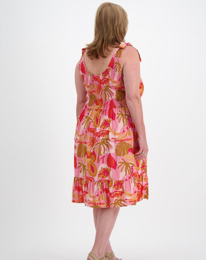 Woman wearing a pink paradise print sun dress on a white background