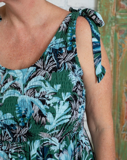 Close-up of a woman wearing a tropical leaf patterned shirred sundress.