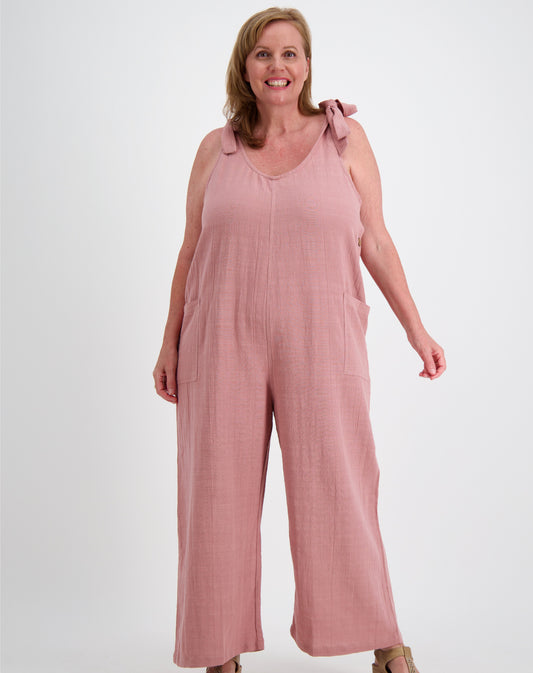 Woman wearing a pink tiestrap jumpsuit by miss seafari on a white background