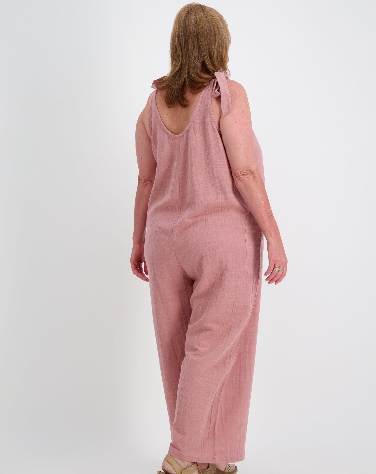 Woman wearing a jumpsuit by miss seafari in blushed pink on a white background