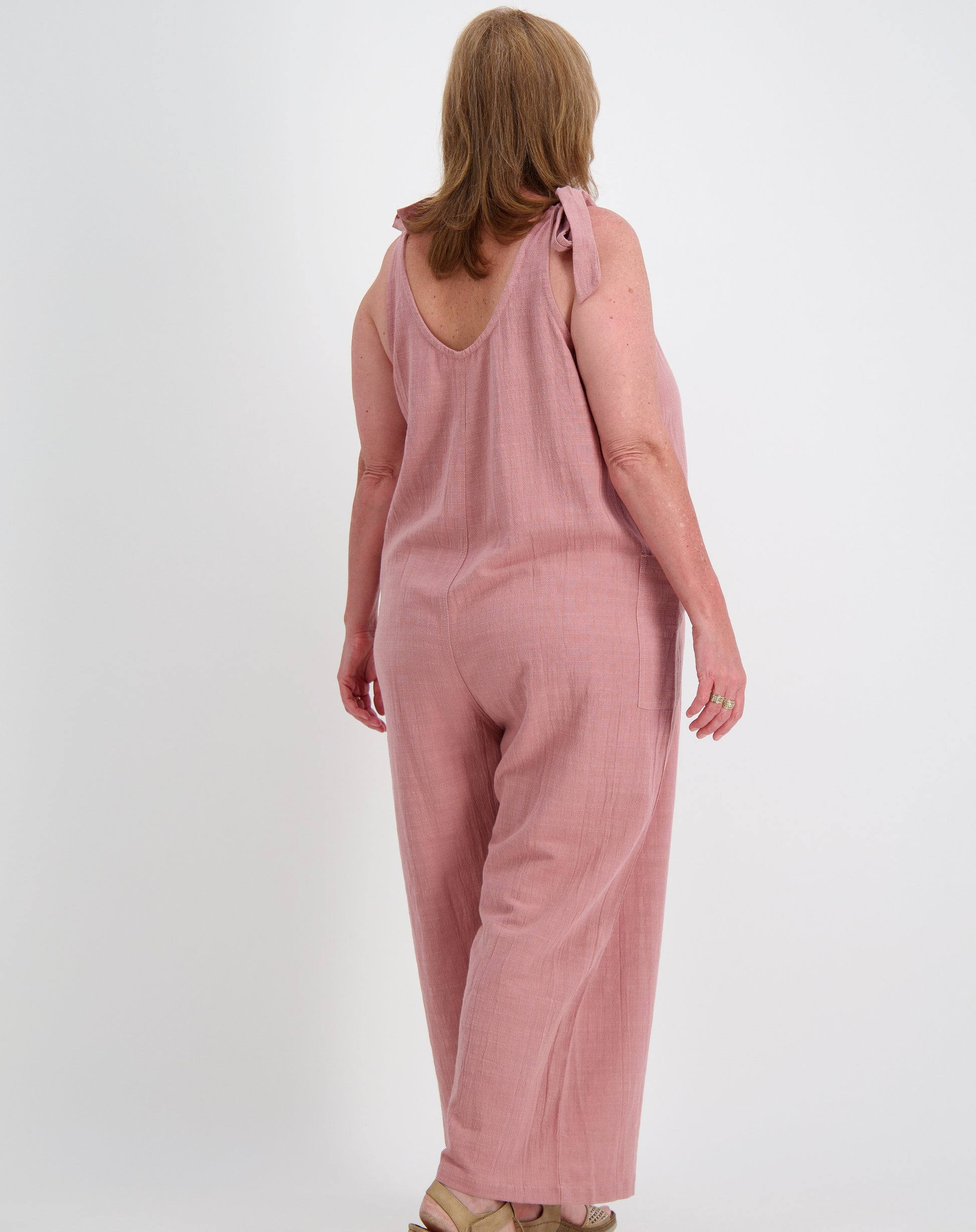 Woman wearing a jumpsuit by miss seafari in blushed pink on a white background