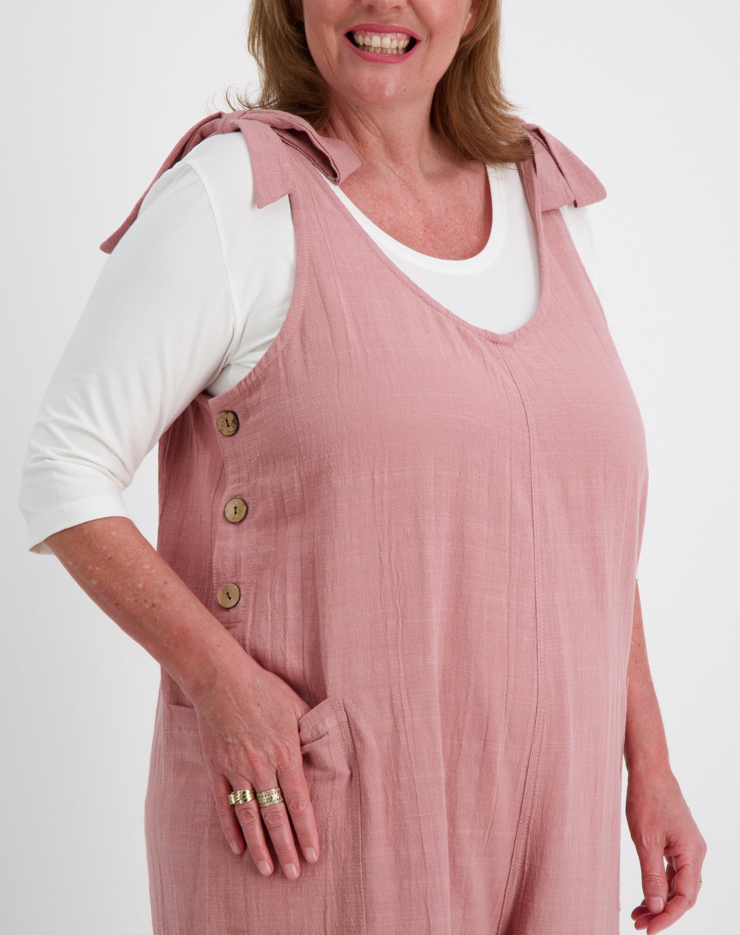 Woman wearing a tiestrap jumpsuit in blush over a white modal tee on a white background