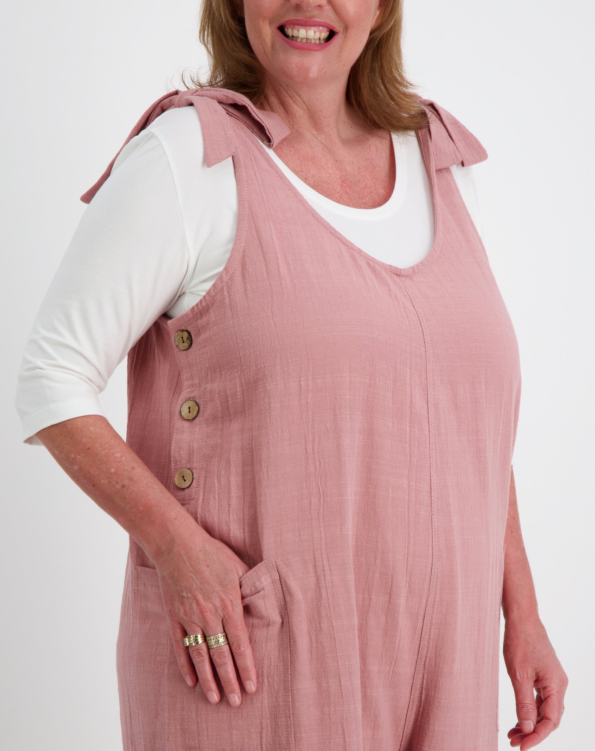 Woman wearing a tiestrap jumpsuit in blush over a white modal tee on a white background