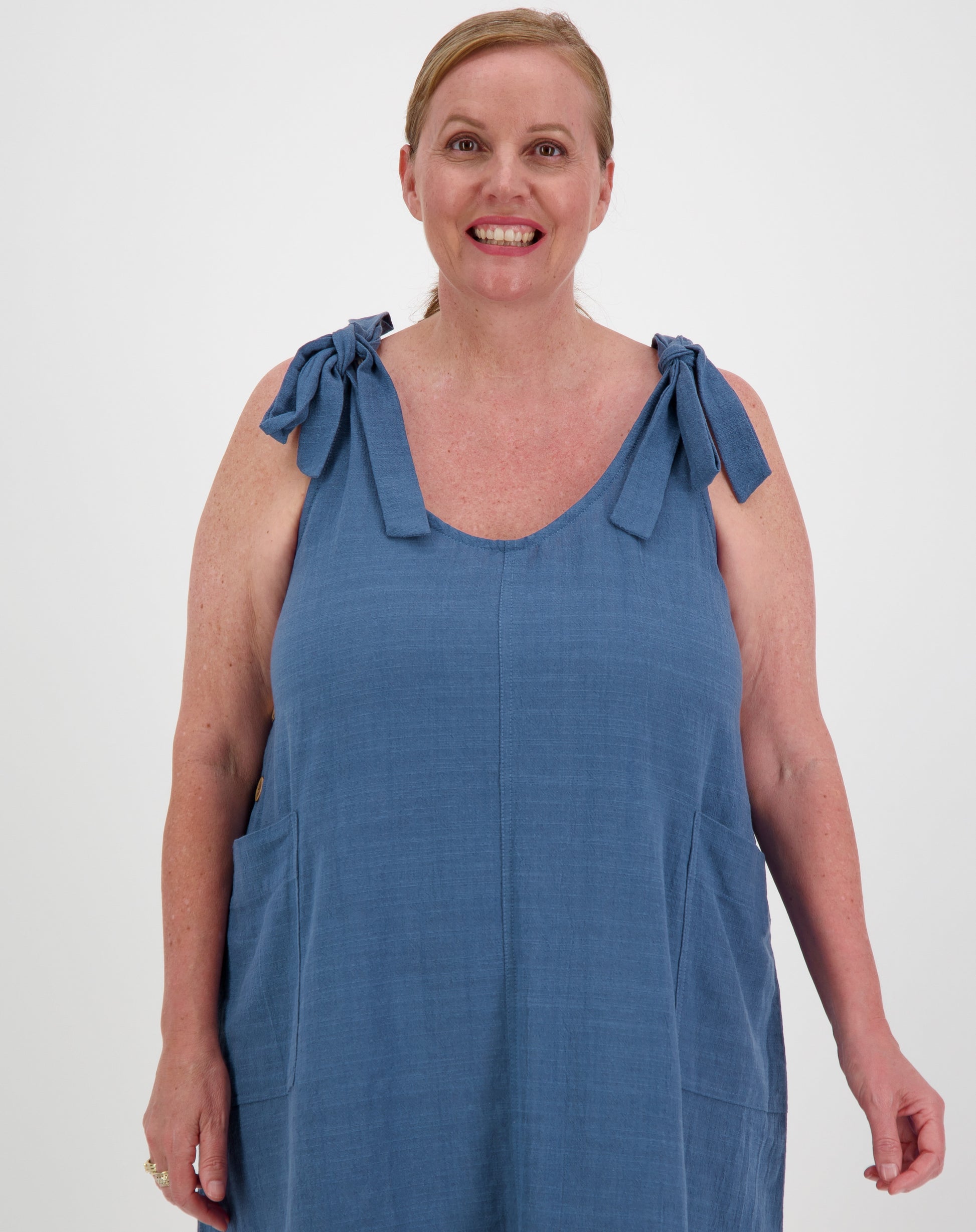 Woman wearing a blue dress with bow straps on a white background