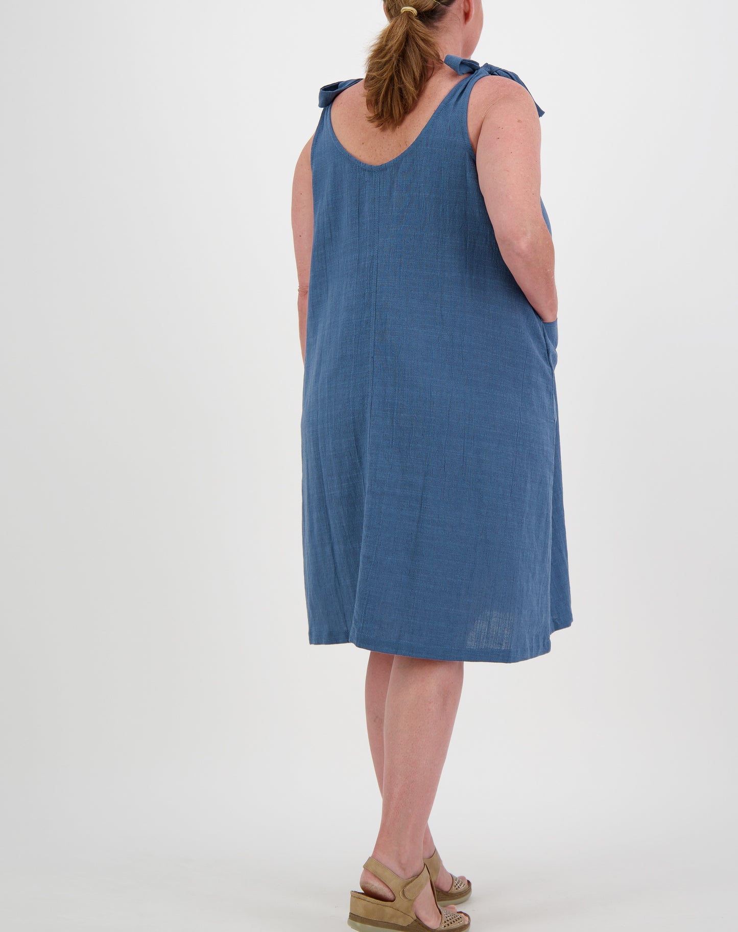 Woman wearing a blue tiestrap smock  dress by miss seafari on a white background