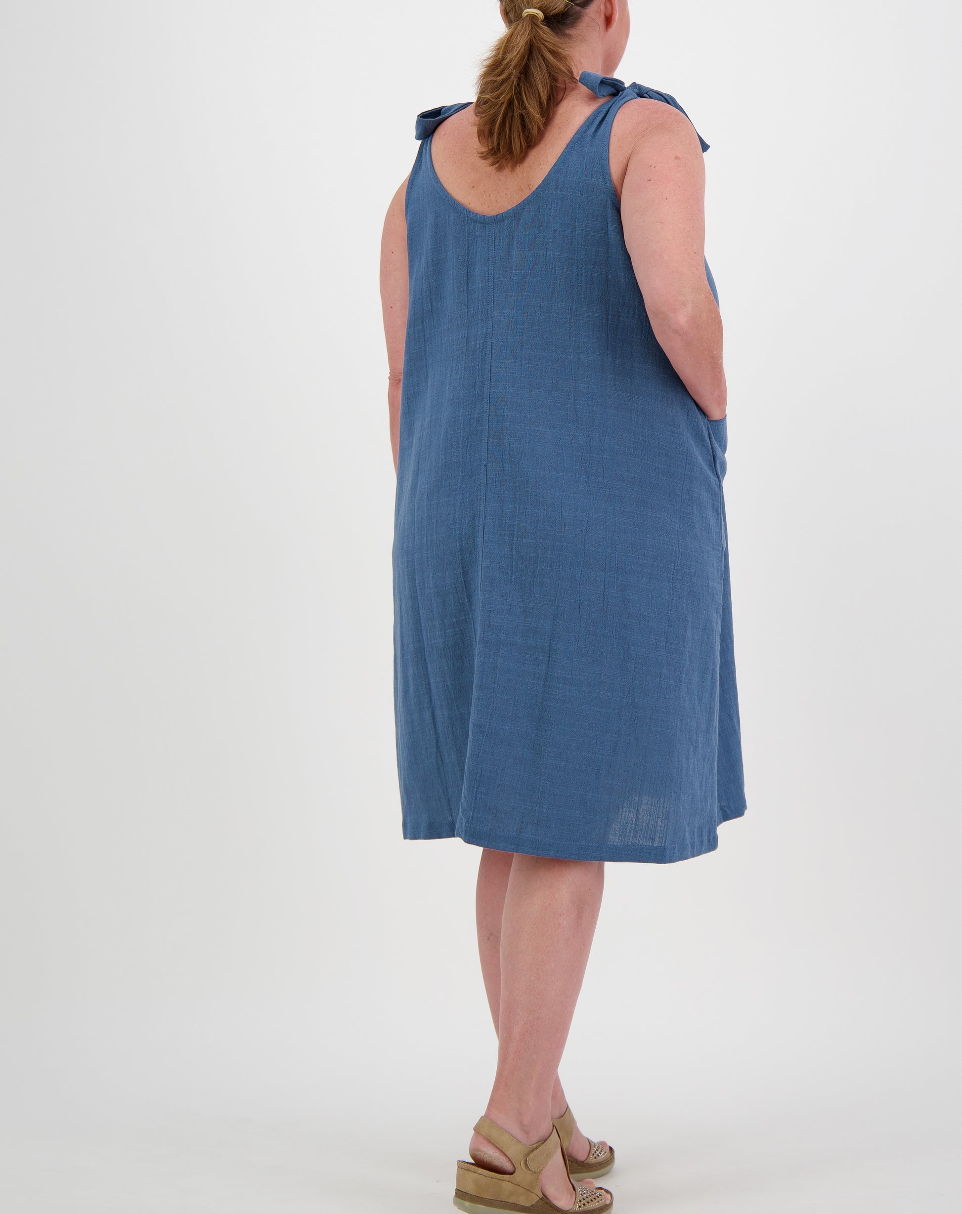 Woman wearing a blue tiestrap smock  dress by miss seafari on a white background