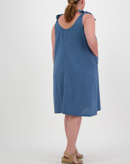 Woman wearing a blue tiestrap smock  dress by miss seafari on a white background